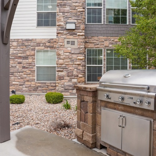 State-of-the-art amenities Outdoor lounge at The Ivy at Draper 55 and over Apartments in Draper, UT, featuring a grill station and brick building.